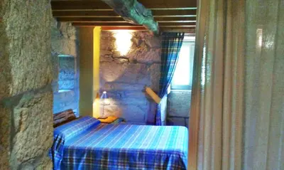 a bedroom with a bed in a stone wall at Rectoral de Prado in Piñeiro