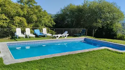 a swimming pool with two chairs and two lawn chairs at Rectoral de Prado in Piñeiro