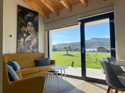 a living room with a couch and a large window at Apartamentos Turísticos VillaCordido Villaframil Ribadeo in Ribadeo
