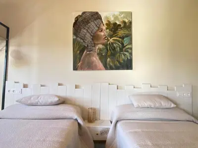 a bedroom with two beds and a painting of a woman at Apartamentos Turísticos VillaCordido Villaframil Ribadeo in Ribadeo