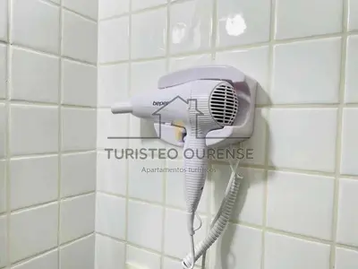 a hair dryer is hanging on a bathroom wall at A morada das perseidas in Ourense