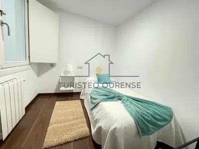 a bedroom with a bed and a white wall at A morada das perseidas in Ourense