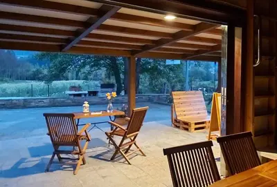 a patio with a wooden table and chairs at Casetón do Forno. in Lourenzá