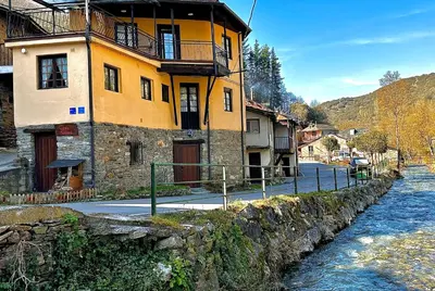 a yellow building on the side of a river at CASA NARCISA - Perfecta para familias y grupos - Valle del Silencio in San Clemente de Valdueza