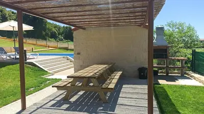 a picnic table and a bench under a pergola at Veiga da Porta - Casa Rural in Ciquiril