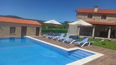 a pool with chairs and umbrellas next to a building at Veiga da Porta - Casa Rural in Ciquiril