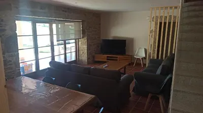 a living room with a couch and a table and a tv at Veiga da Porta - Casa Rural in Ciquiril
