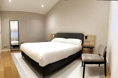 a bedroom with a large white bed and a chair at H7072 Luxury apartments in Santiago de Compostela