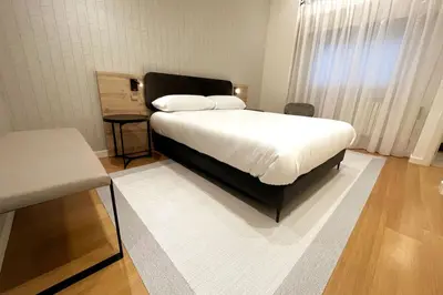 a bedroom with a bed with a white blanket and a table at H7072 Luxury apartments in Santiago de Compostela