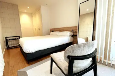 a bedroom with a bed and a chair and a mirror at H7072 Luxury apartments in Santiago de Compostela