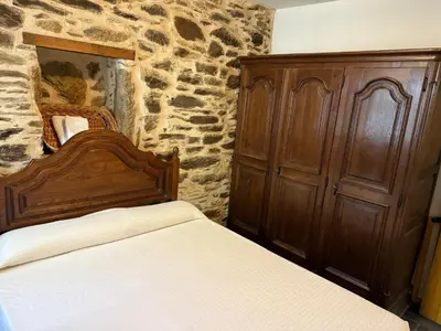 a bedroom with a wooden bed and a stone wall at Casa Rural Los Cabritos de Tomás in Puebla de Sanabria