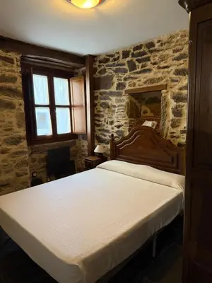 a bedroom with a bed and a stone wall at Casa Rural Los Cabritos de Tomás in Puebla de Sanabria