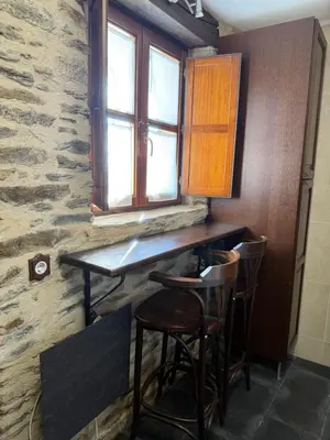 a kitchen with a bar with stools under a window at Casa Rural Los Cabritos de Tomás in Puebla de Sanabria