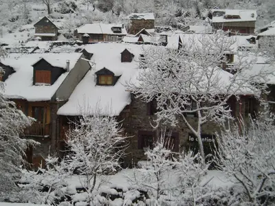 a house covered in snow with trees and houses at Casa Trallera in Colinas del Campo de Martín Moro