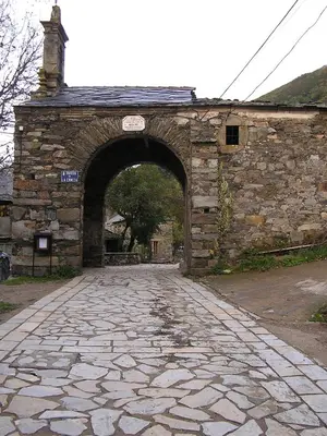 an old stone building with an arch in a road at Casa Trallera in Colinas del Campo de Martín Moro