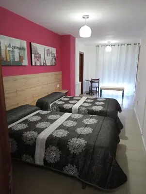 two beds in a room with pink walls at O novo alto do couso in Ourense