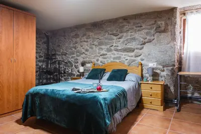 a bedroom with a bed and a stone wall at Villa Vaquiña in Airoa