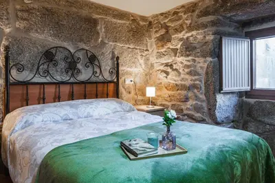 a bedroom with a bed and a stone wall at Villa Vaquiña in Airoa