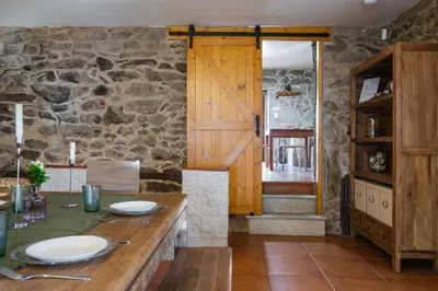 a dining room with a table and a stone wall at Villa Vaquiña in Airoa
