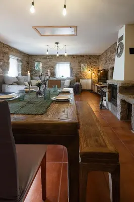 a large wooden table in a living room with a fireplace at Villa Vaquiña in Airoa