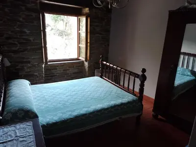 a bedroom with a bed and a stone wall at Casa Arza in Tríacastela