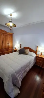 a bedroom with a large white bed and two night stands at Apartamentos Tesón Ribadeo in Ribadeo