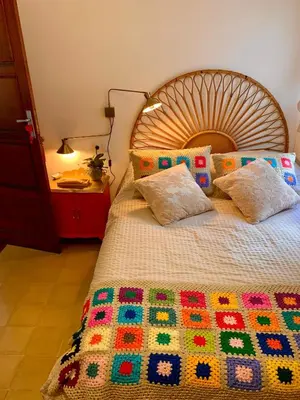 a bed with a wooden headboard and a colorful blanket at Alojamiento estilo Boho con mucho encanto in Ponferrada