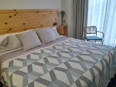 a bedroom with a bed with a wooden headboard and a chair at Lumen Place APARTAMENTOS in Mondoñedo