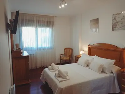 a bedroom with a bed with white sheets and a window at Martínez Rooms Pilgrims in Caldas de Reis