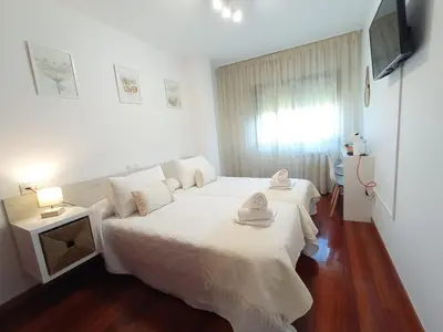 a white bedroom with two beds and a television at Martínez Rooms Pilgrims in Caldas de Reis