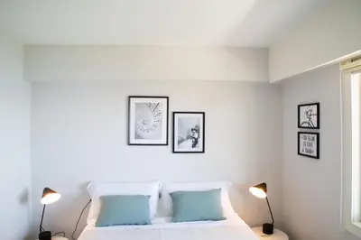 a white bedroom with a bed and three pictures on the wall at Apartamento Playa Lago in A Coruña