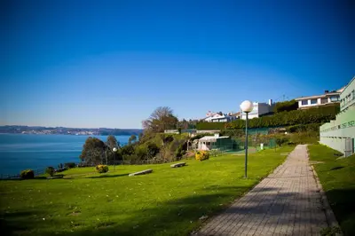 a walkway next to a field of grass next to the water at Apartamento Playa Lago in A Coruña