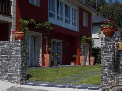 a red house with potted plants in front of it at Apartamentos Guidan in Ribadeo