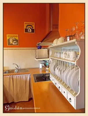a kitchen with a sink and a shelf with dishes at Apartamentos Guidan in Ribadeo