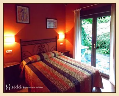 a bedroom with a bed with orange walls and a window at Apartamentos Guidan in Ribadeo