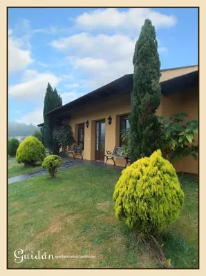 a house with a large yard with benches and trees at Apartamentos Guidan in Ribadeo
