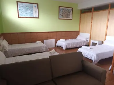 a room with three beds and a couch in it at A CONDA-habitación privada in Arzúa