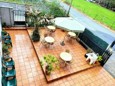 a patio with tables and chairs and an umbrella at A CONDA-habitación privada in Arzúa