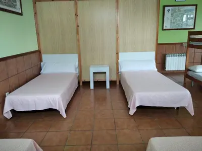 a room with two beds and a table in it at A CONDA-habitación privada in Arzúa