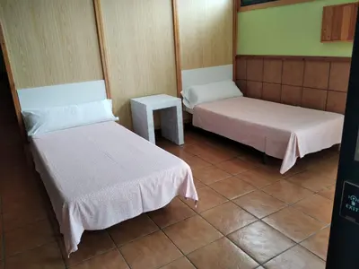 a room with two beds and a table at A CONDA-habitación privada in Arzúa
