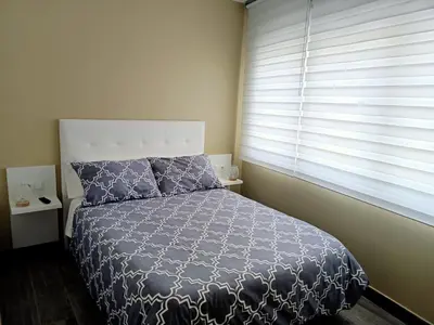 a bedroom with a bed with a blue comforter and a window at O Abeiro do Eume in Puentedeume
