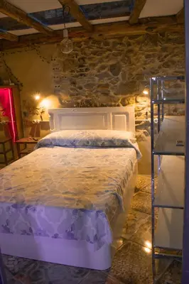 a bedroom with a white bed in a stone wall at Casa en zona medieval in Monforte de Lemos