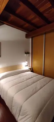a bedroom with a large white bed with a wooden headboard at Apartamentos Turísticos Betanzos in Betanzos