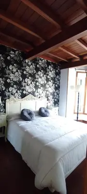 a bedroom with a white bed with floral wallpaper at Apartamentos Turísticos Betanzos in Betanzos