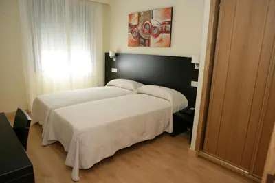 a bedroom with a large bed with white sheets at HOTEL BRUMA II in La Gudiña