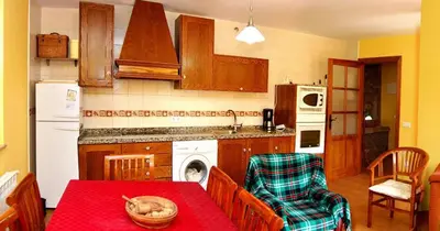 a kitchen with a table and a kitchen with a stove and refrigerator at Casa Rural Las Verdes l y II in Torre de Babia
