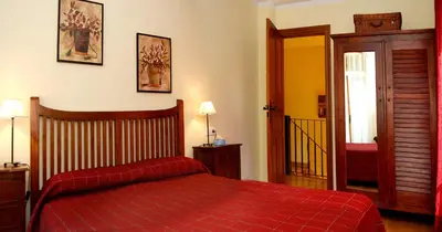 a bedroom with a bed with a red bedspread at Casa Rural Las Verdes l y II in Torre de Babia