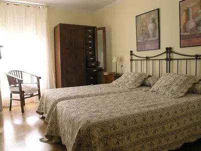 a bedroom with a bed and a chair and a window at Casa Rural Las Verdes l y II in Torre de Babia
