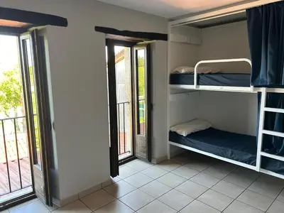 a room with three bunk beds in a room with windows at Albergue San Anton in Melide