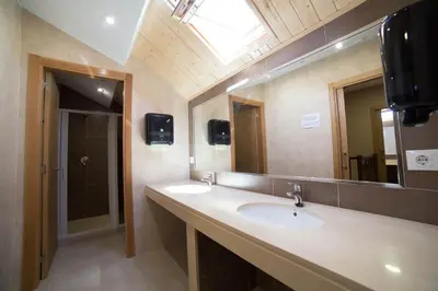a bathroom with two sinks and a large mirror at Albergue San Anton in Melide